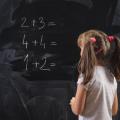Skolejente med musefletter skriver tall på en tavle