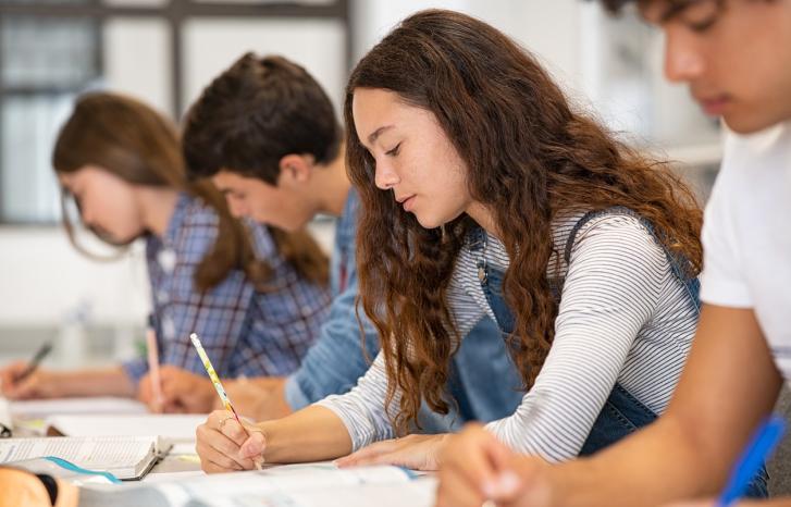Fire ungdommer sitter i et klasserom og skriver