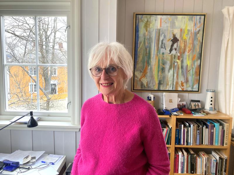 Kari Melby hjemme, foran bokhyllen
